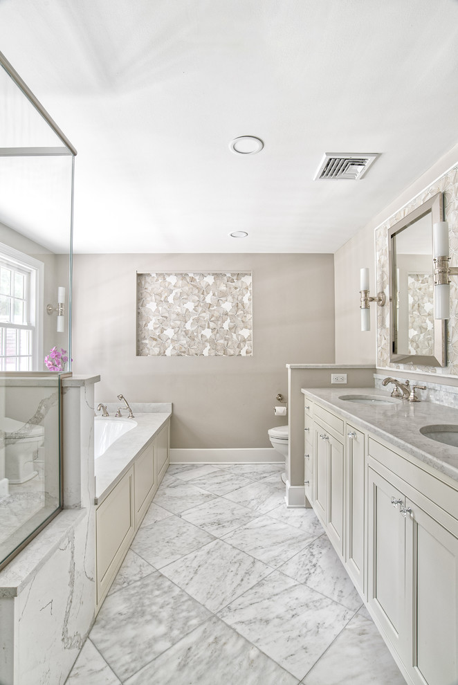 Photo of a large traditional master bathroom in New York with beaded inset cabinets, an undermount tub, white tile, mosaic tile, marble floors, an undermount sink, quartzite benchtops, white floor, a hinged shower door and white benchtops.