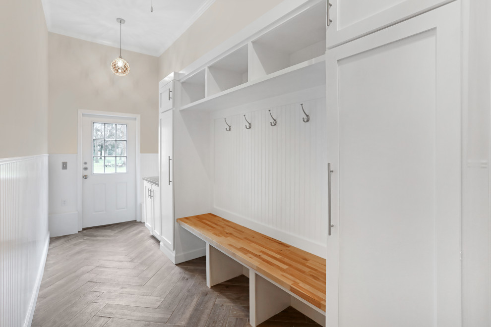 This is an example of a mid-sized transitional mudroom in New York with beige walls, laminate floors, a single front door, a white front door, beige floor, recessed and decorative wall panelling.