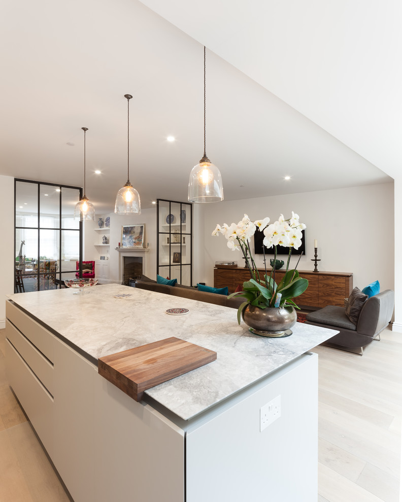 Mid-sized contemporary l-shaped eat-in kitchen in London with a drop-in sink, flat-panel cabinets, white cabinets, marble benchtops, brown splashback, timber splashback, coloured appliances, light hardwood floors, with island and brown floor.