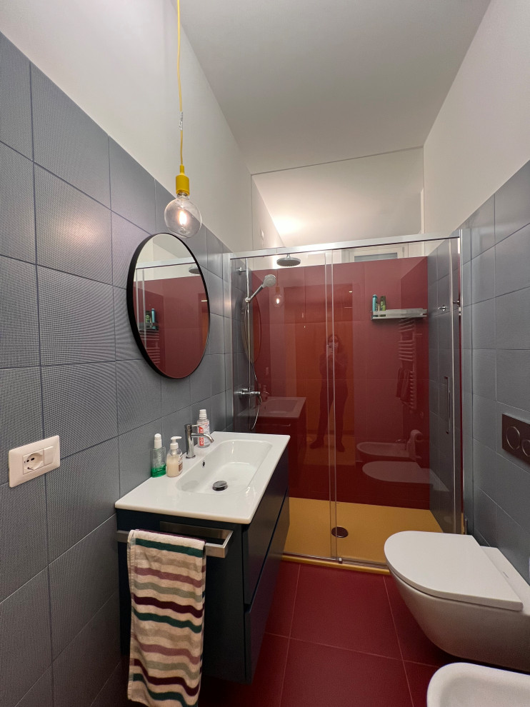 Стильный дизайн: детская ванная комната среднего размера в стиле модернизм с синими фасадами, душем без бортиков, раздельным унитазом, разноцветной плиткой, керамогранитной плиткой, белыми стенами, полом из керамогранита, монолитной раковиной, красным полом, душем с раздвижными дверями, белой столешницей, тумбой под одну раковину и подвесной тумбой - последний тренд