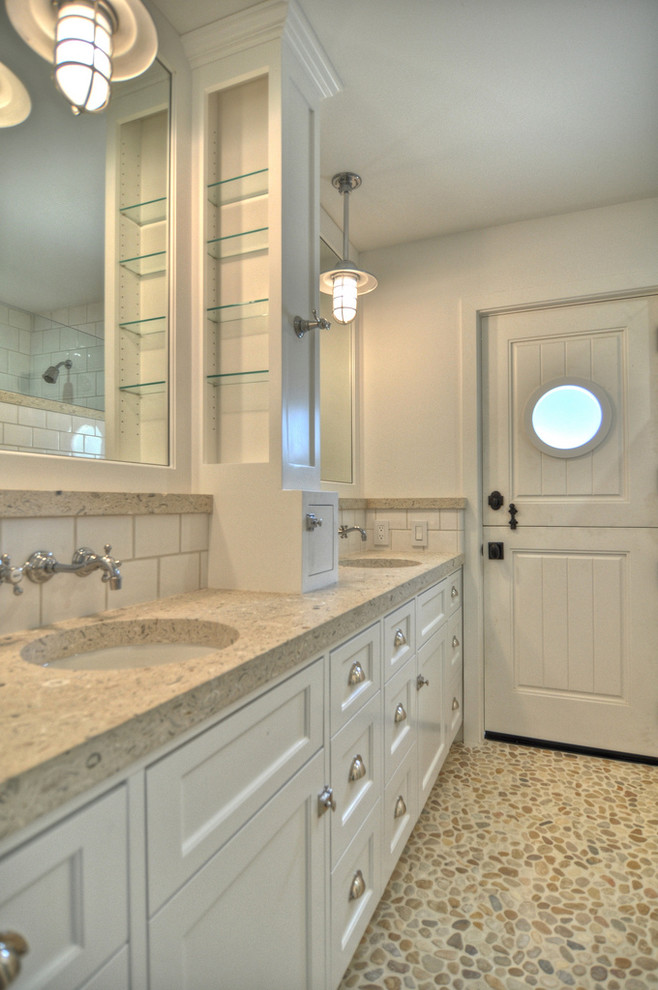 Beach style bathroom in Orange County with an undermount sink, recessed-panel cabinets, white cabinets, concrete benchtops, an open shower, a one-piece toilet, white tile, ceramic tile, white walls and pebble tile floors.