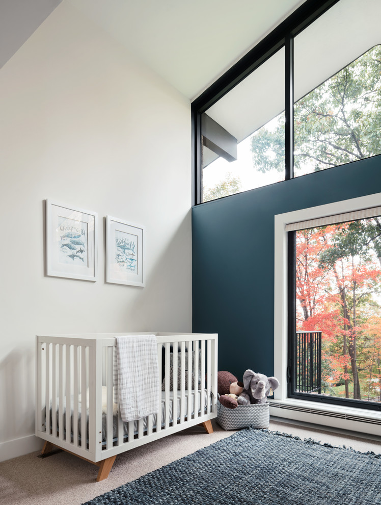 This is an example of a large midcentury nursery for boys in New York with blue walls and carpet.