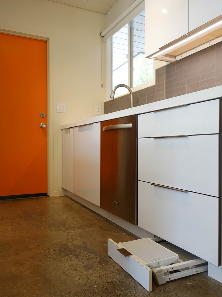 Inspiration for a mid-sized midcentury galley eat-in kitchen in San Francisco with an undermount sink, flat-panel cabinets, white cabinets, quartz benchtops, grey splashback, ceramic splashback, stainless steel appliances, concrete floors, with island, grey floor and white benchtop.