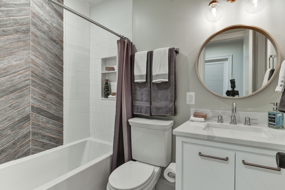 This is an example of a transitional bathroom in DC Metro with shaker cabinets, white cabinets, an alcove tub, a shower/bathtub combo, gray tile, white tile, grey walls, an undermount sink, a shower curtain, white benchtops and a single vanity.