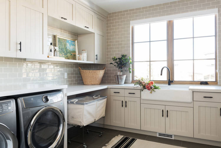 This is an example of a large transitional u-shaped laundry room in Salt Lake City with a farmhouse sink, beige cabinets, ceramic floors and grey floor.