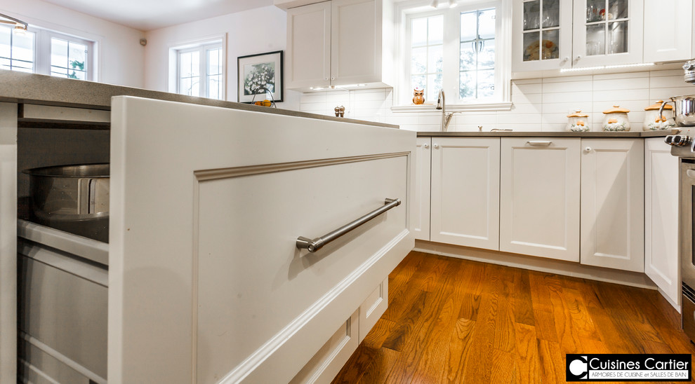 Large transitional medium tone wood floor eat-in kitchen photo in Montreal with a double-bowl sink, shaker cabinets, white cabinets, quartzite countertops, white backsplash, ceramic backsplash, stainless steel appliances and an island