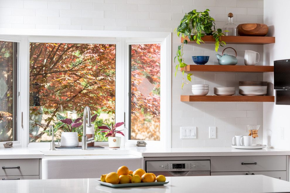 Open concept kitchen - mid-sized transitional u-shaped light wood floor and brown floor open concept kitchen idea with a farmhouse sink, shaker cabinets, gray cabinets, quartz countertops, white backsplash, ceramic backsplash, stainless steel appliances, a peninsula and white countertops
