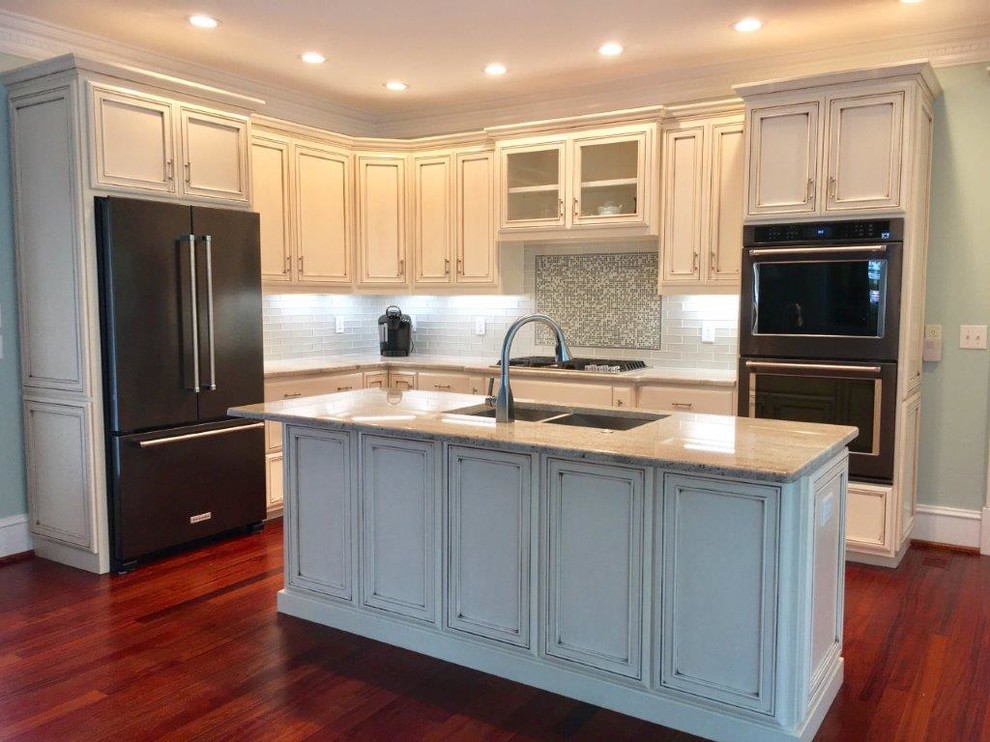 Design ideas for a mid-sized transitional l-shaped separate kitchen in Raleigh with a double-bowl sink, beaded inset cabinets, beige cabinets, granite benchtops, grey splashback, glass tile splashback, black appliances, dark hardwood floors, with island, red floor and beige benchtop.