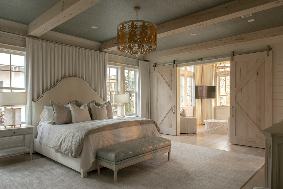 Photo of a large beach style master bedroom in Other with white walls, beige floor and light hardwood floors.