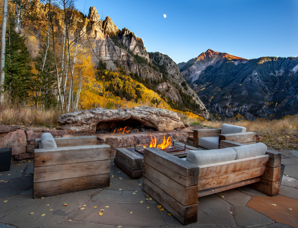 Inspiration for an expansive country backyard patio in Denver with natural stone pavers, no cover and a fire feature.