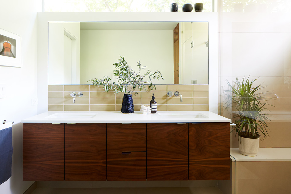 Inspiration for a midcentury master bathroom in San Francisco with flat-panel cabinets, dark wood cabinets, beige tile, white walls, an undermount sink and white benchtops.
