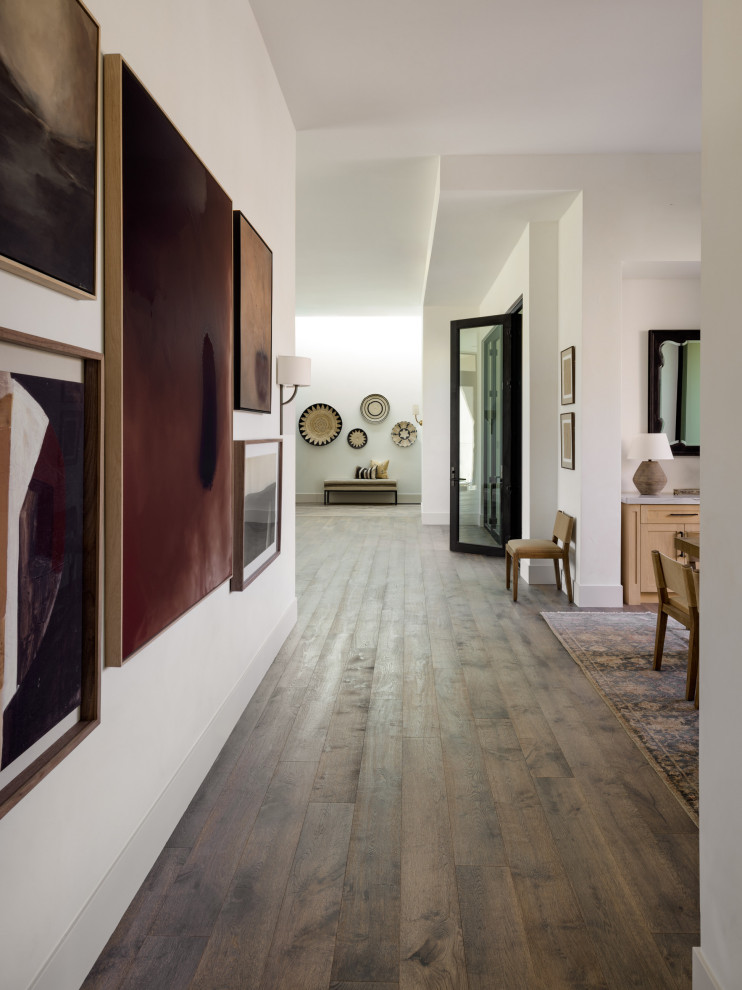 Example of a huge southwest medium tone wood floor and brown floor hallway design in Other with white walls