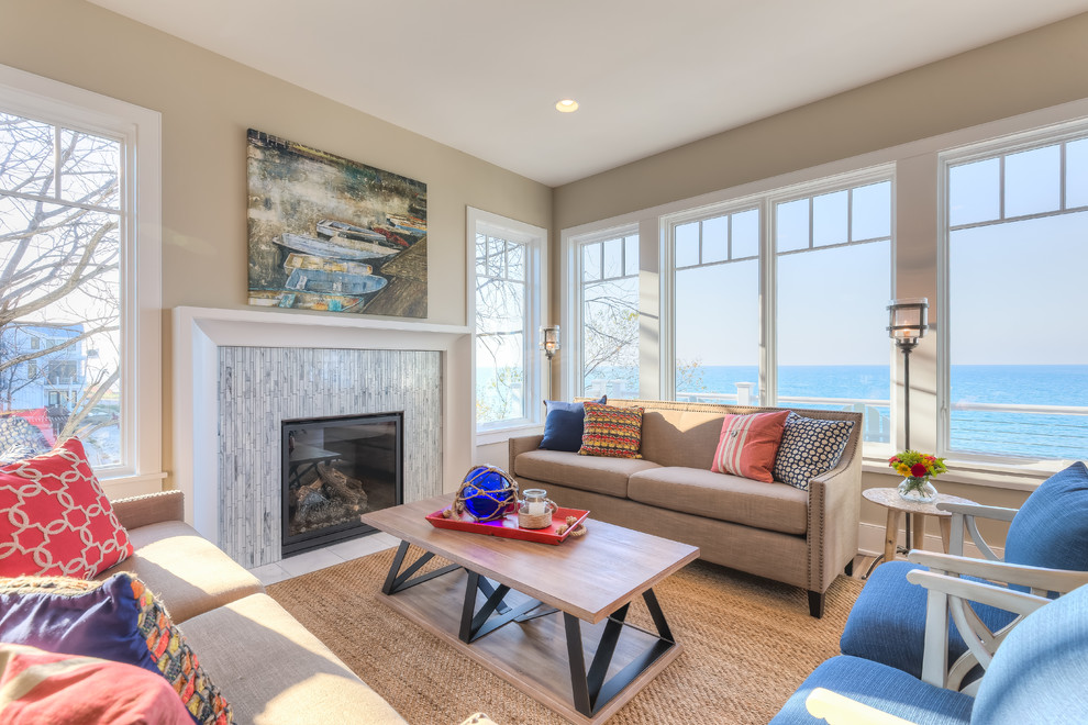 Mid-sized beach style formal enclosed living room in Chicago with beige walls, a standard fireplace, a tile fireplace surround, light hardwood floors and a wall-mounted tv.