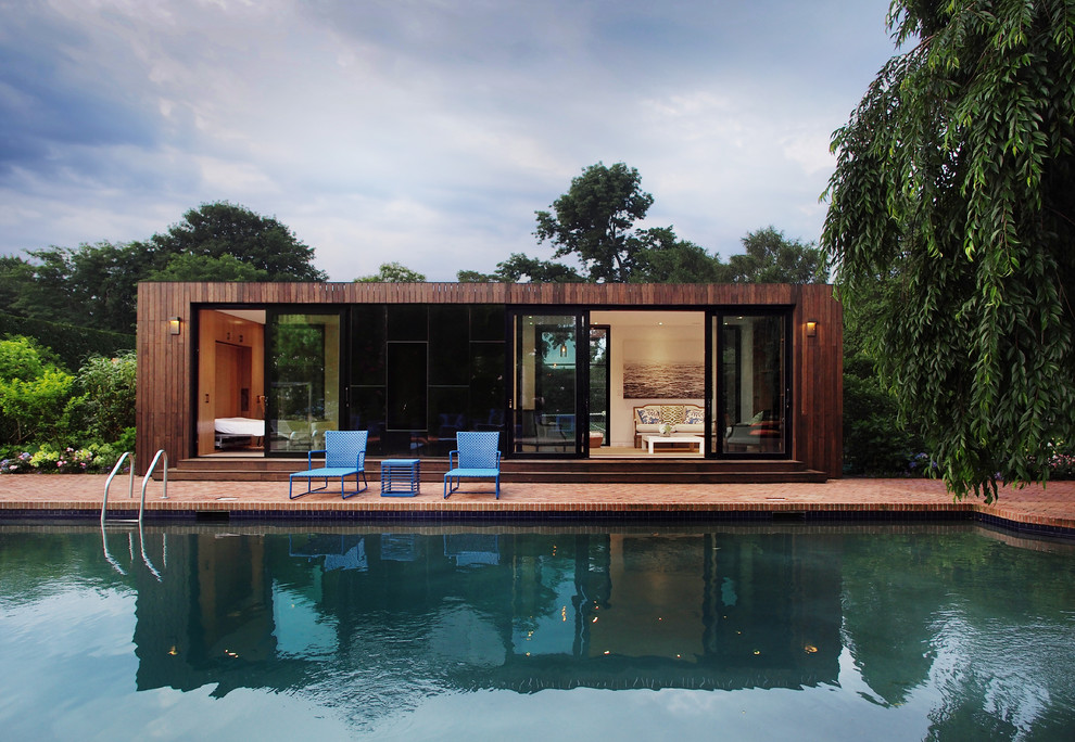 Modern pool in New York with a pool house and brick pavers.
