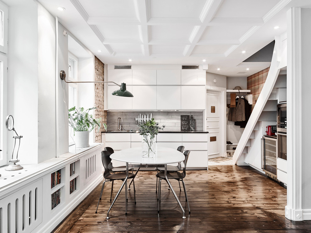 Photo of a mid-sized scandinavian single-wall eat-in kitchen in Gothenburg with flat-panel cabinets, white cabinets, grey splashback, dark hardwood floors, no island and stainless steel appliances.