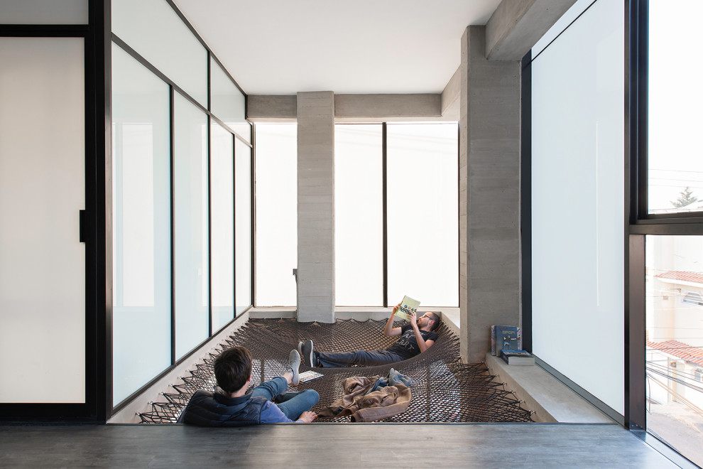 Идея дизайна: изолированная гостиная комната среднего размера в современном стиле с с книжными шкафами и полками, бетонным полом, серым полом, балками на потолке, серыми стенами и панелями на части стены без камина, телевизора
