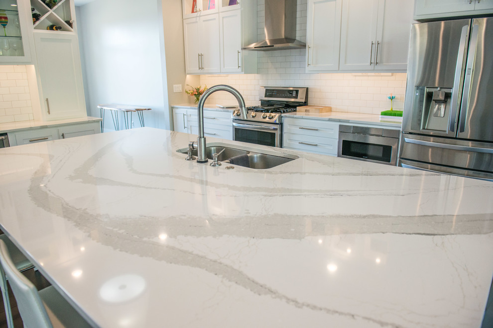 Example of a huge transitional l-shaped dark wood floor and brown floor open concept kitchen design in Chicago with a double-bowl sink, shaker cabinets, white cabinets, quartz countertops, white backsplash, ceramic backsplash, stainless steel appliances and an island