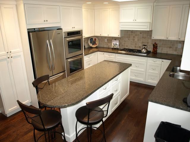 Inspiration for a mid-sized transitional u-shaped eat-in kitchen in Vancouver with an undermount sink, recessed-panel cabinets, white cabinets, terrazzo benchtops, beige splashback, ceramic splashback, stainless steel appliances, medium hardwood floors, with island and brown floor.