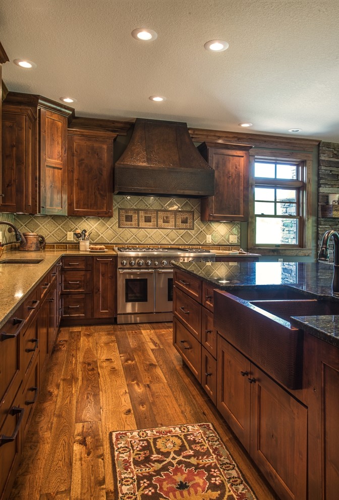 Country u-shaped eat-in kitchen in Charleston with a farmhouse sink, recessed-panel cabinets, distressed cabinets, granite benchtops, green splashback, porcelain splashback, stainless steel appliances, medium hardwood floors and with island.