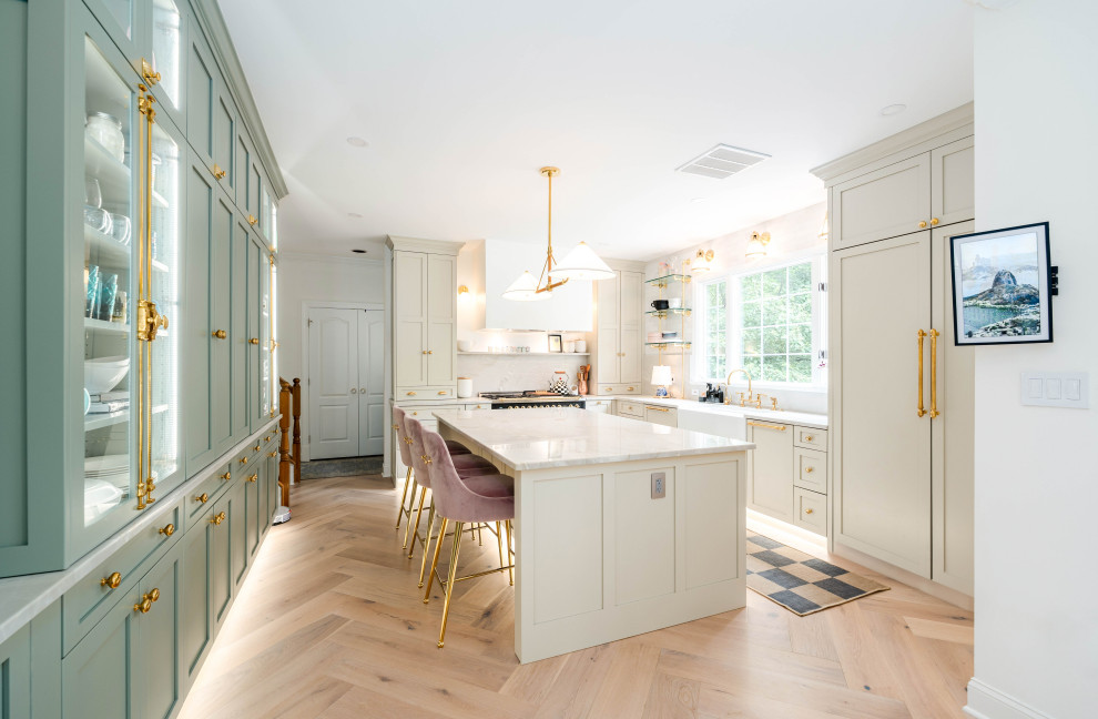 Design ideas for a large u-shaped eat-in kitchen in DC Metro with a farmhouse sink, shaker cabinets, green cabinets, quartzite benchtops, white splashback, porcelain splashback, black appliances, light hardwood floors, with island, grey floor and white benchtop.
