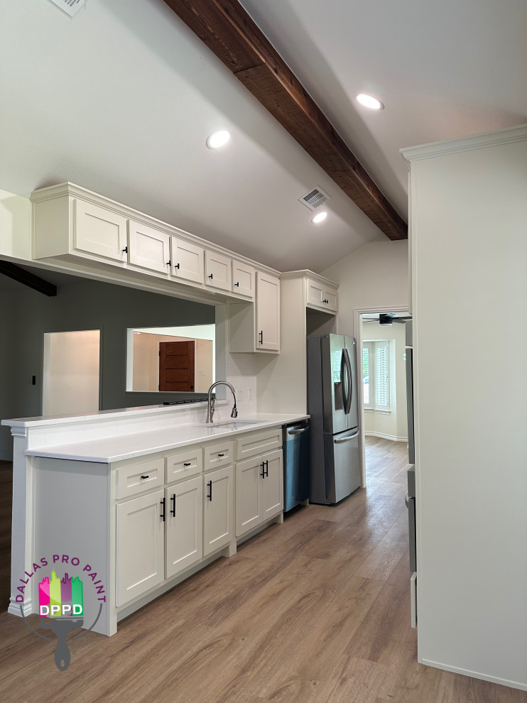 This is an example of an expansive contemporary dedicated laundry room in Dallas with an undermount sink, quartz benchtops, white walls, a side-by-side washer and dryer, brown floor, white benchtop and exposed beam.