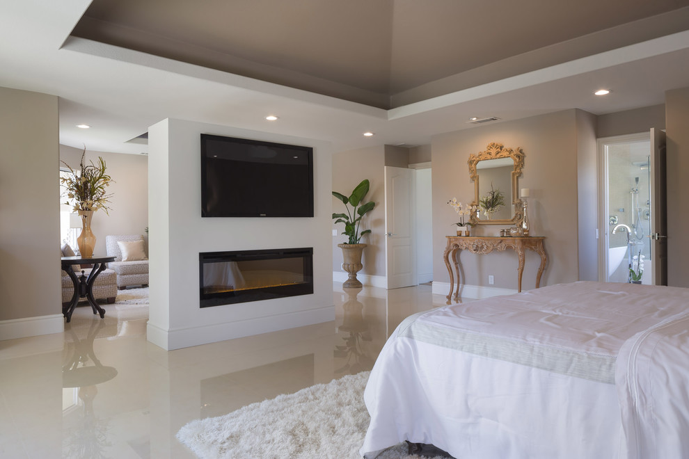 Expansive contemporary master bedroom in Los Angeles with grey walls, porcelain floors, a ribbon fireplace, a plaster fireplace surround and beige floor.