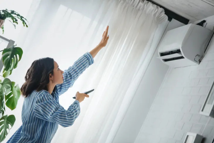 woman reaching to see if air conditioning is working