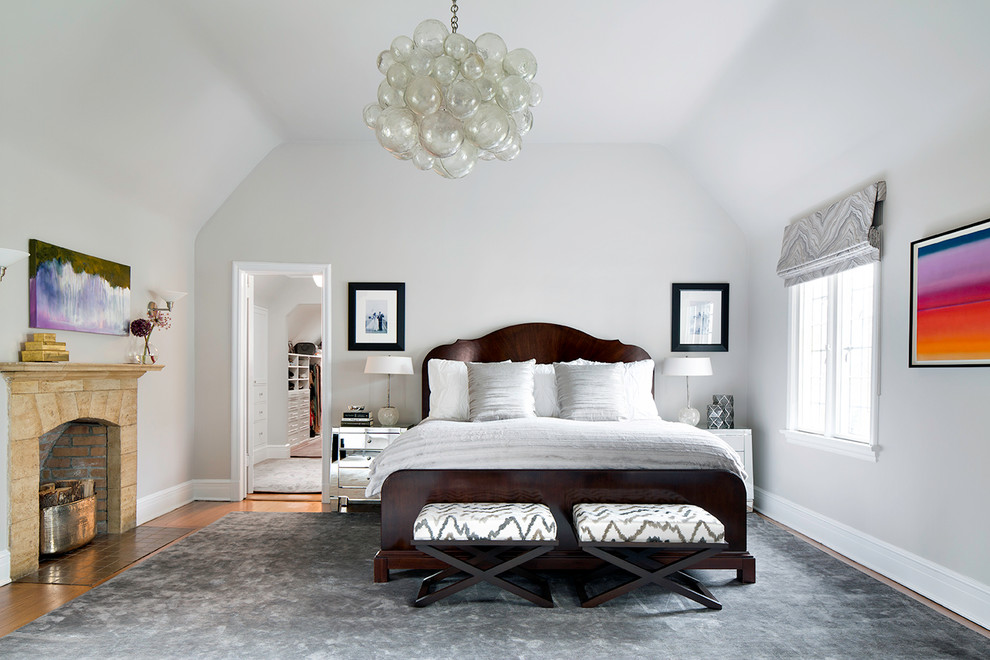 This is an example of a transitional bedroom in New York with white walls and a standard fireplace.