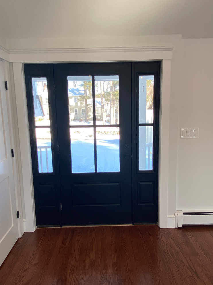 Стильный дизайн: входная дверь в стиле кантри с белыми стенами, паркетным полом среднего тона, одностворчатой входной дверью, черной входной дверью, коричневым полом и сводчатым потолком - последний тренд
