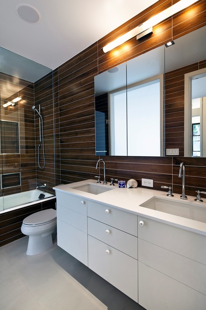 Design ideas for a mid-sized modern master bathroom in New York with an undermount sink, flat-panel cabinets, white cabinets, a shower/bathtub combo, brown tile, brown walls, an alcove tub, a two-piece toilet, porcelain tile, concrete floors and solid surface benchtops.