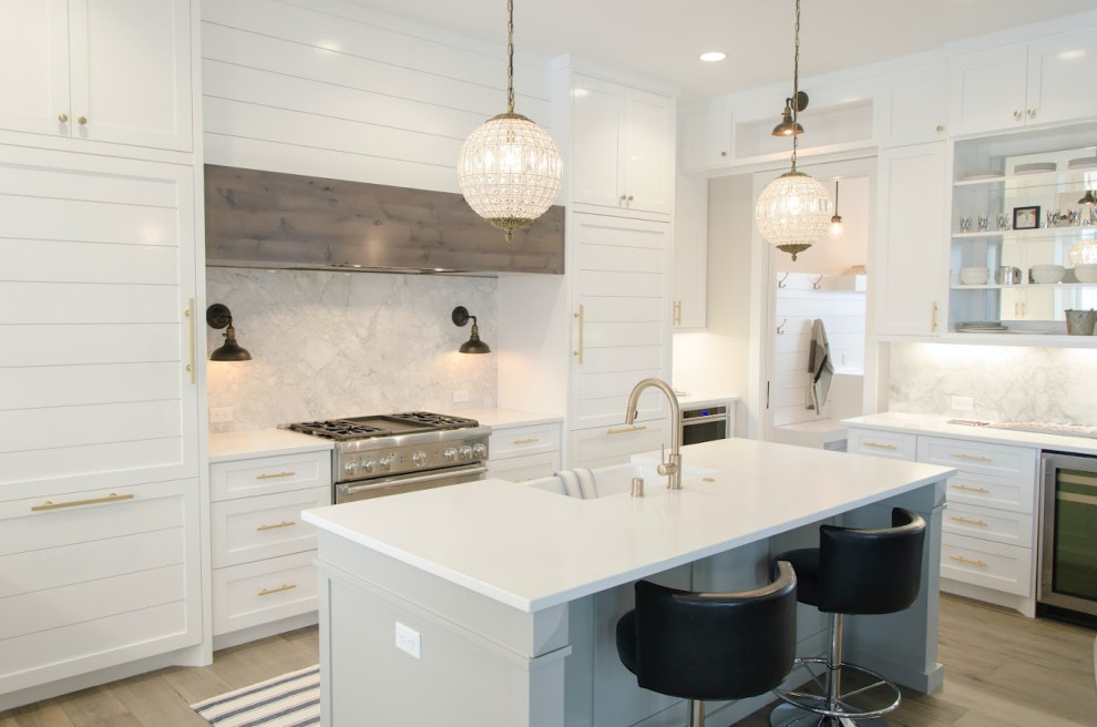 This is an example of a mid-sized modern kitchen in Tampa with raised-panel cabinets, white cabinets, stainless steel appliances and with island.