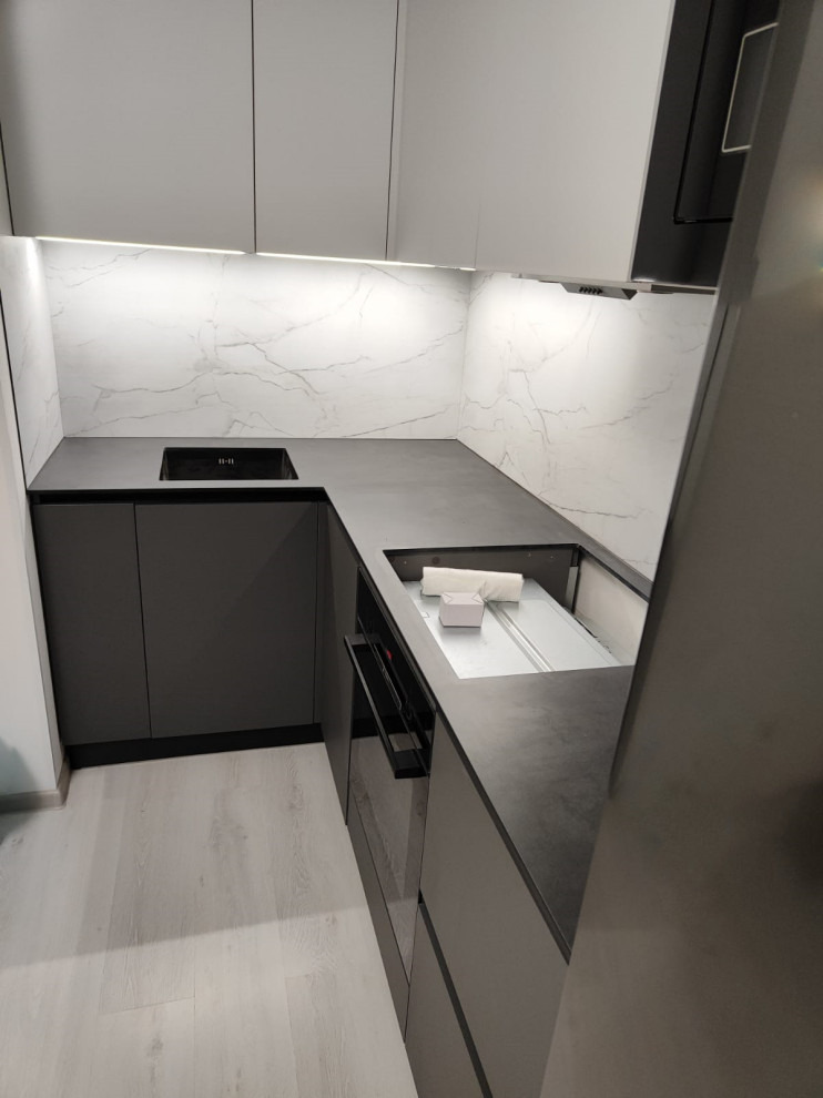 Inspiration for a mid-sized modern l-shaped eat-in kitchen in Saint Petersburg with an undermount sink, laminate benchtops, white splashback, black appliances, no island and grey benchtop.