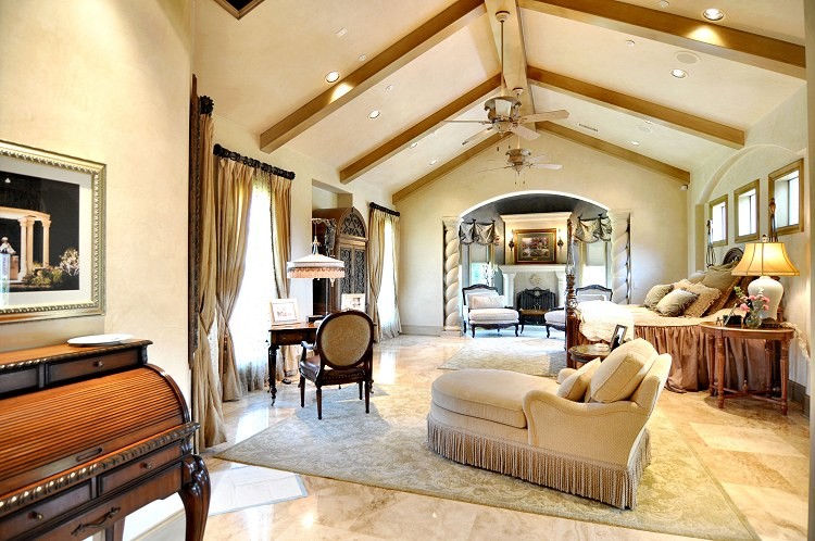 This is an example of a large traditional master bedroom in Dallas with beige walls, travertine floors and no fireplace.