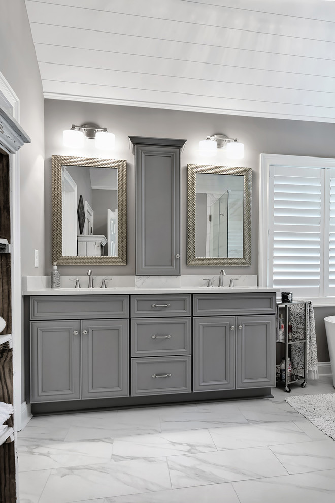 Design ideas for a large contemporary master bathroom in Charleston with recessed-panel cabinets, grey cabinets, a freestanding tub, a corner shower, a two-piece toilet, white tile, porcelain tile, grey walls, porcelain floors, an undermount sink, engineered quartz benchtops, white floor and a hinged shower door.