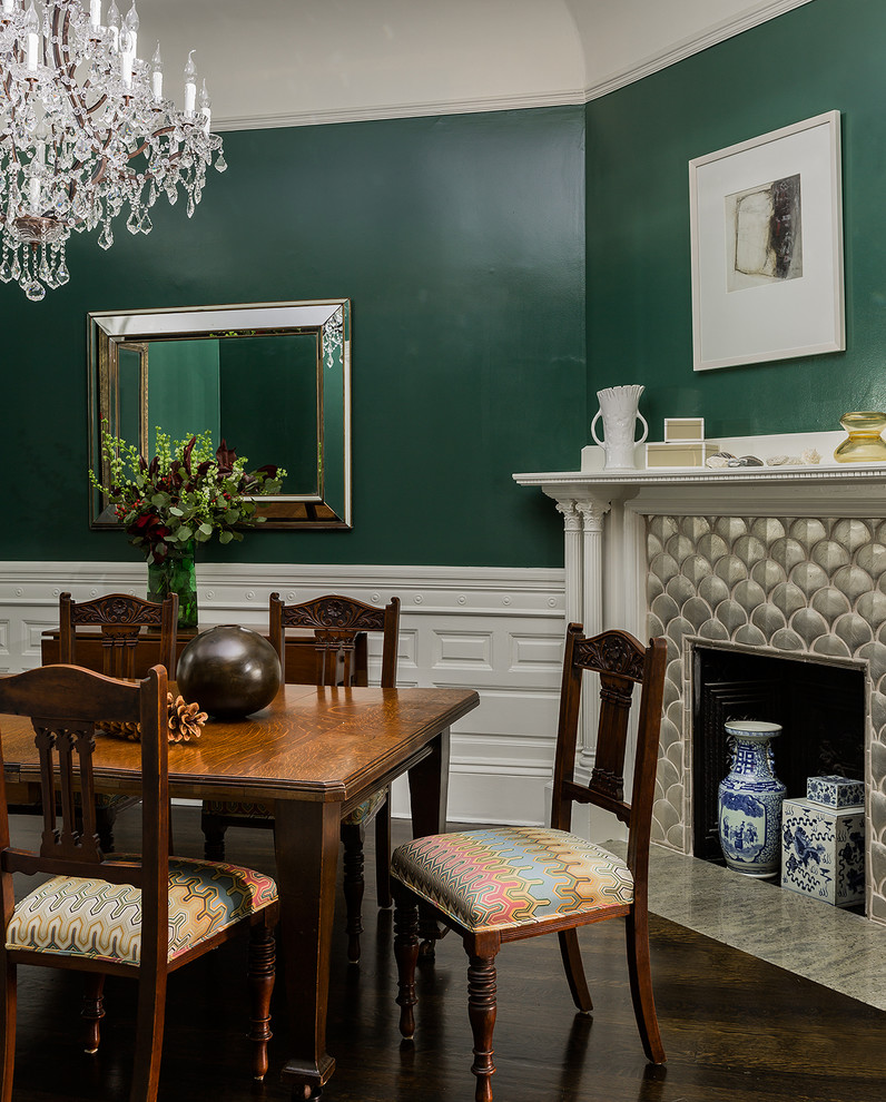 Photo of a large traditional separate dining room in Boston with green walls, dark hardwood floors, a standard fireplace, a plaster fireplace surround and brown floor.