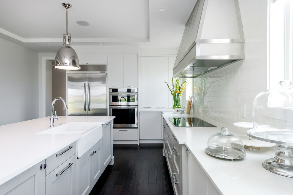Inspiration for a large transitional l-shaped dark wood floor eat-in kitchen remodel in Calgary with a farmhouse sink, flat-panel cabinets, quartz countertops, white backsplash, subway tile backsplash, stainless steel appliances and an island