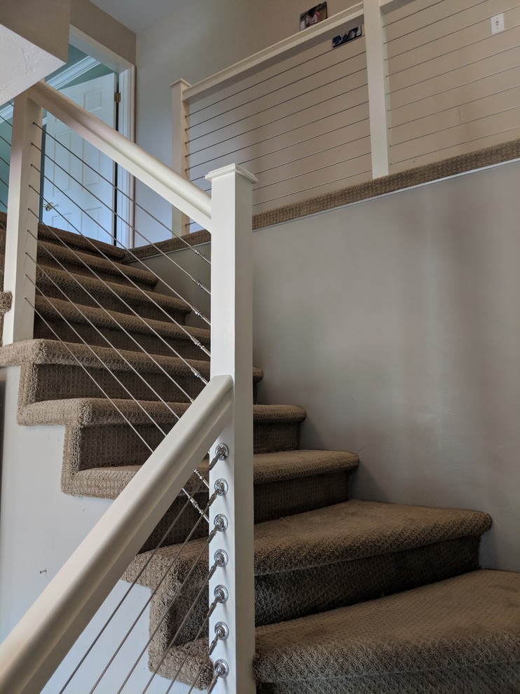 На фото: угловая лестница среднего размера в стиле модернизм с ступенями с ковровым покрытием, ковровыми подступенками и перилами из тросов