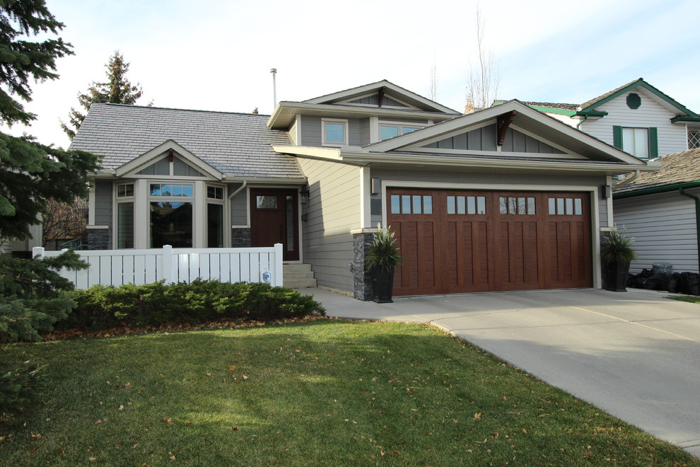 This is an example of a large traditional split-level grey house exterior in Calgary with concrete fiberboard siding, a gable roof and a shingle roof.