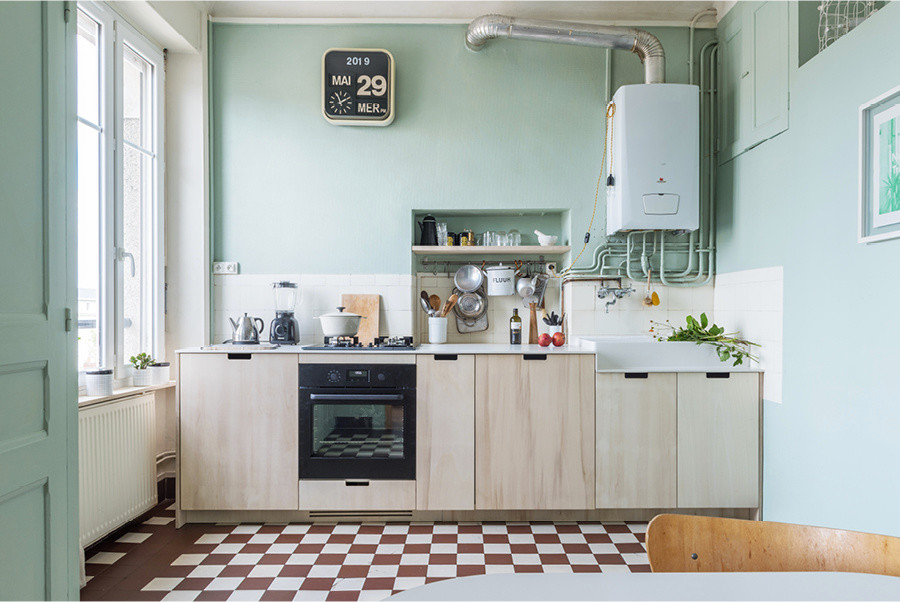 Photo of a small scandinavian single-wall open plan kitchen in Nantes with a farmhouse sink, beaded inset cabinets, black appliances, ceramic floors, white benchtop, light wood cabinets, solid surface benchtops, ceramic splashback, no island and red floor.