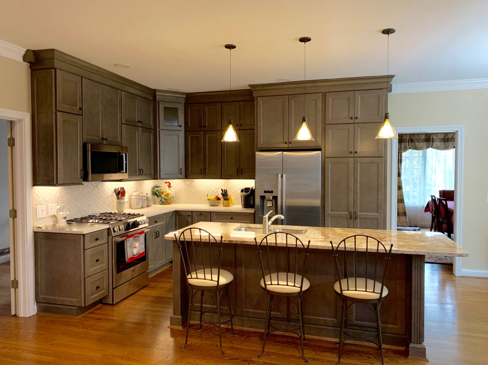 Mid-sized transitional u-shaped medium tone wood floor and brown floor eat-in kitchen photo in Cincinnati with an undermount sink, recessed-panel cabinets, gray cabinets, quartz countertops, white backsplash, stainless steel appliances, an island, white countertops and ceramic backsplash