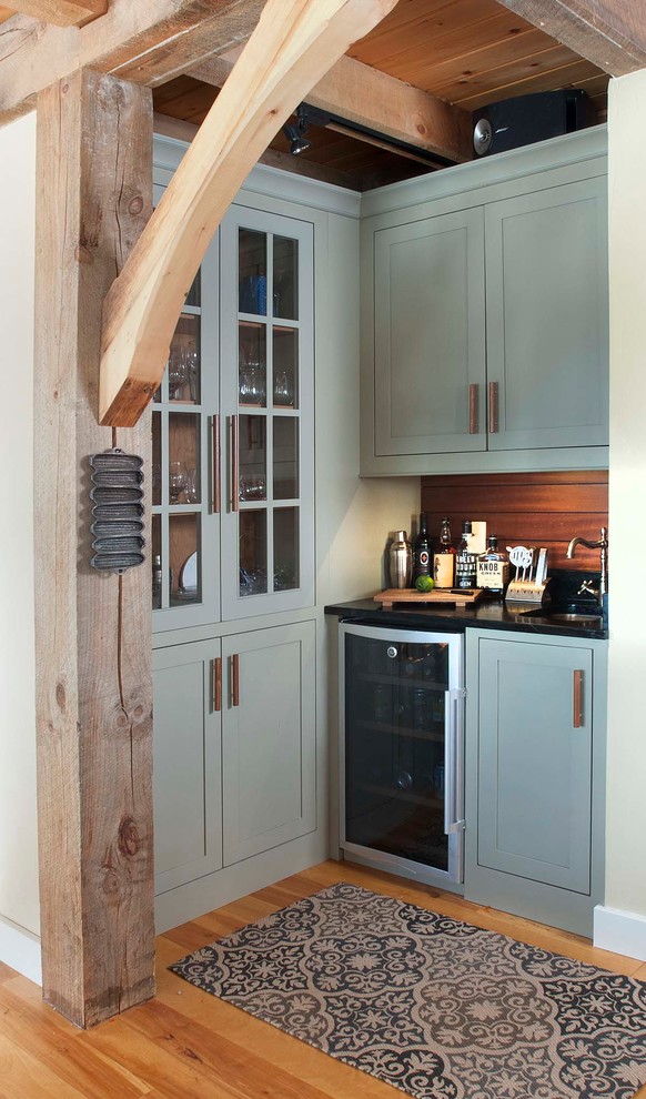 This is an example of a country wet bar in Burlington with an undermount sink, glass-front cabinets, medium hardwood floors and blue cabinets.