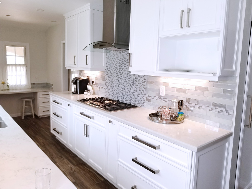 This is an example of a small traditional galley separate kitchen in Los Angeles with an undermount sink, recessed-panel cabinets, white cabinets, quartz benchtops, grey splashback, glass tile splashback, stainless steel appliances, porcelain floors, no island and brown floor.