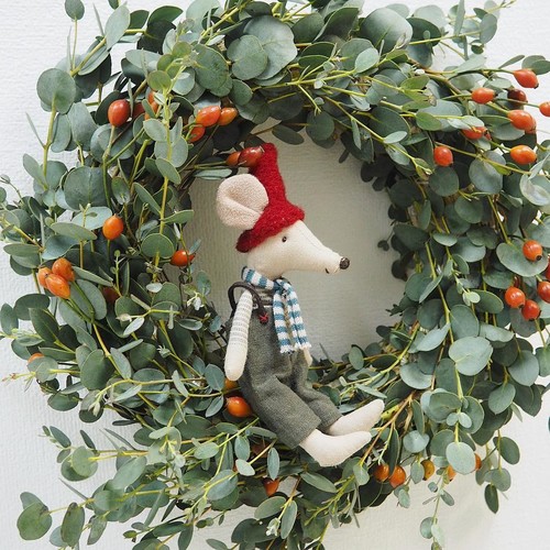 Handmade Christmas mouse sitting inside a eucalyptus holiday wreath with red berries.