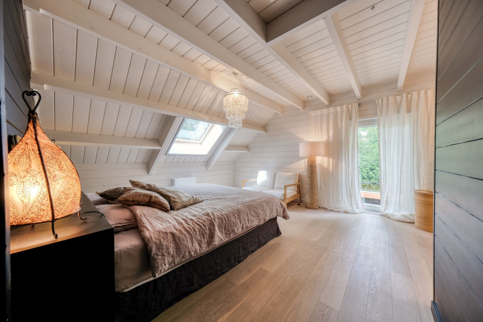 Cette image montre une grande chambre parentale nordique en bois avec parquet clair.