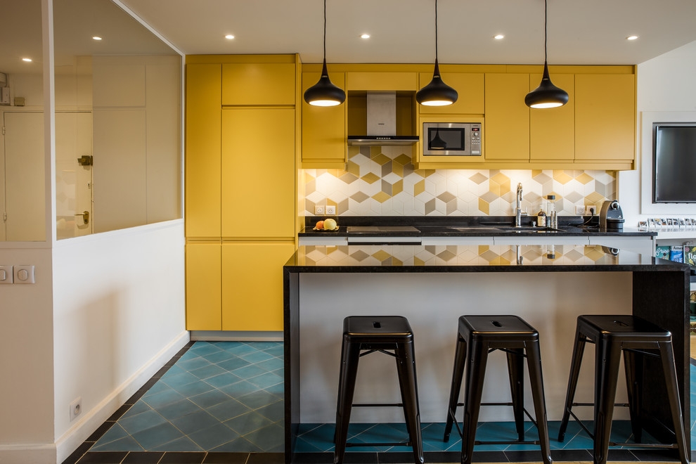 Photo of a mid-sized scandinavian single-wall eat-in kitchen in Paris with a double-bowl sink, yellow cabinets, yellow splashback, porcelain splashback, stainless steel appliances, ceramic floors, with island, blue floor and black benchtop.