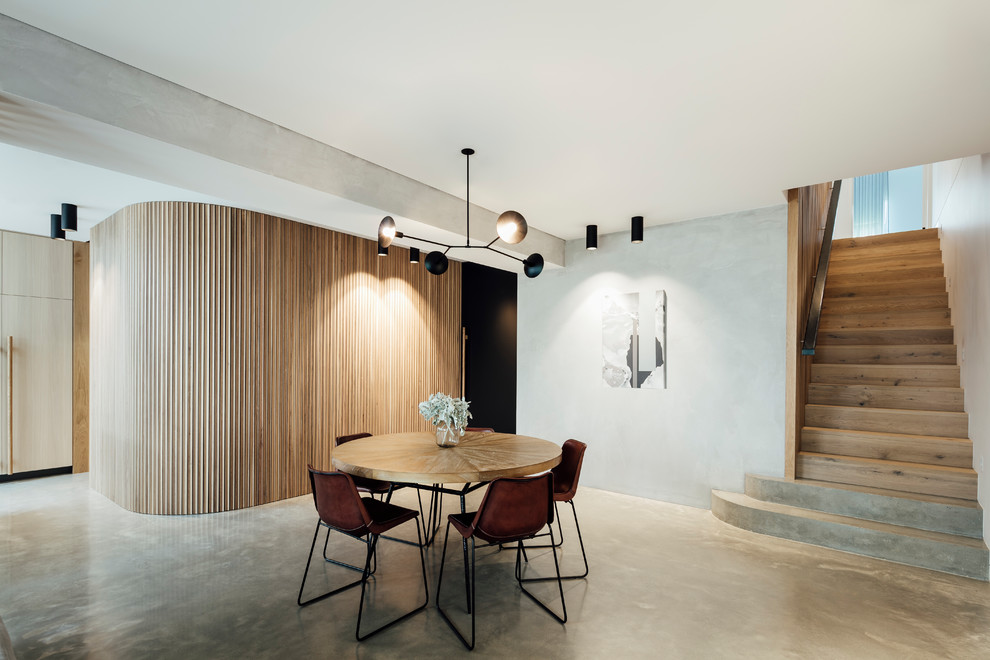 Photo of a contemporary dining room in Melbourne with grey walls, concrete floors and grey floor.