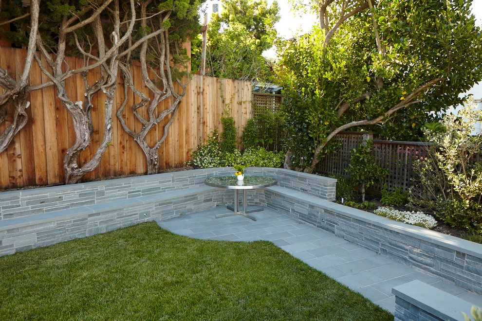This is an example of a mid-sized contemporary backyard partial sun garden in San Francisco with a retaining wall and natural stone pavers.