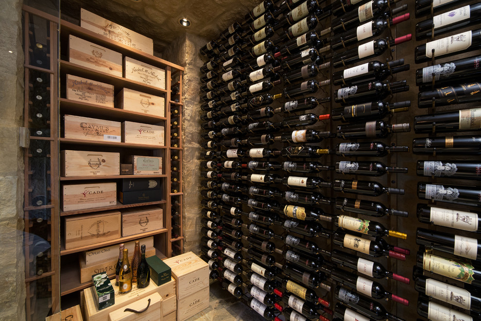 This is an example of a mid-sized transitional wine cellar in Phoenix with limestone floors and storage racks.