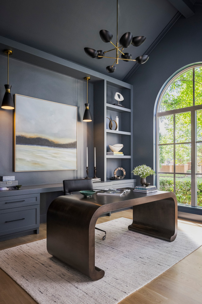 Large transitional freestanding desk light wood floor, brown floor and wall paneling home office photo in Dallas with blue walls