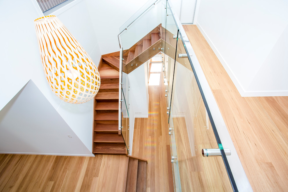 This is an example of a mid-sized contemporary wood l-shaped staircase in Sunshine Coast with wood risers and glass railing.